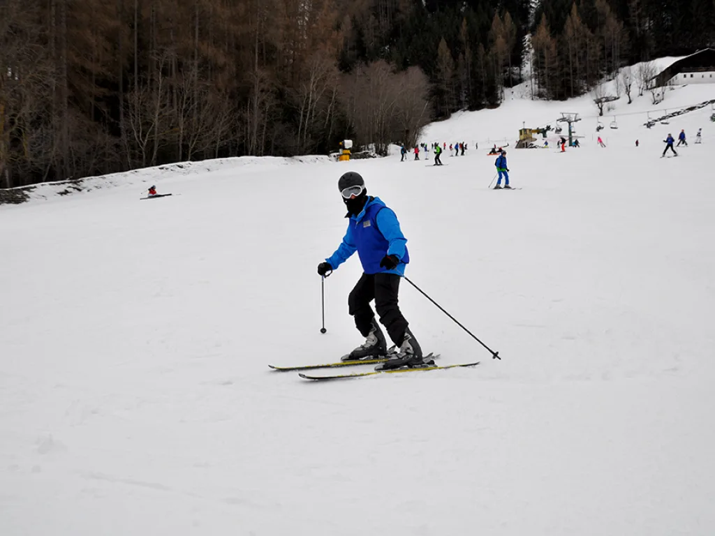 Skifahrer fährt eine breite Piste hinunter.